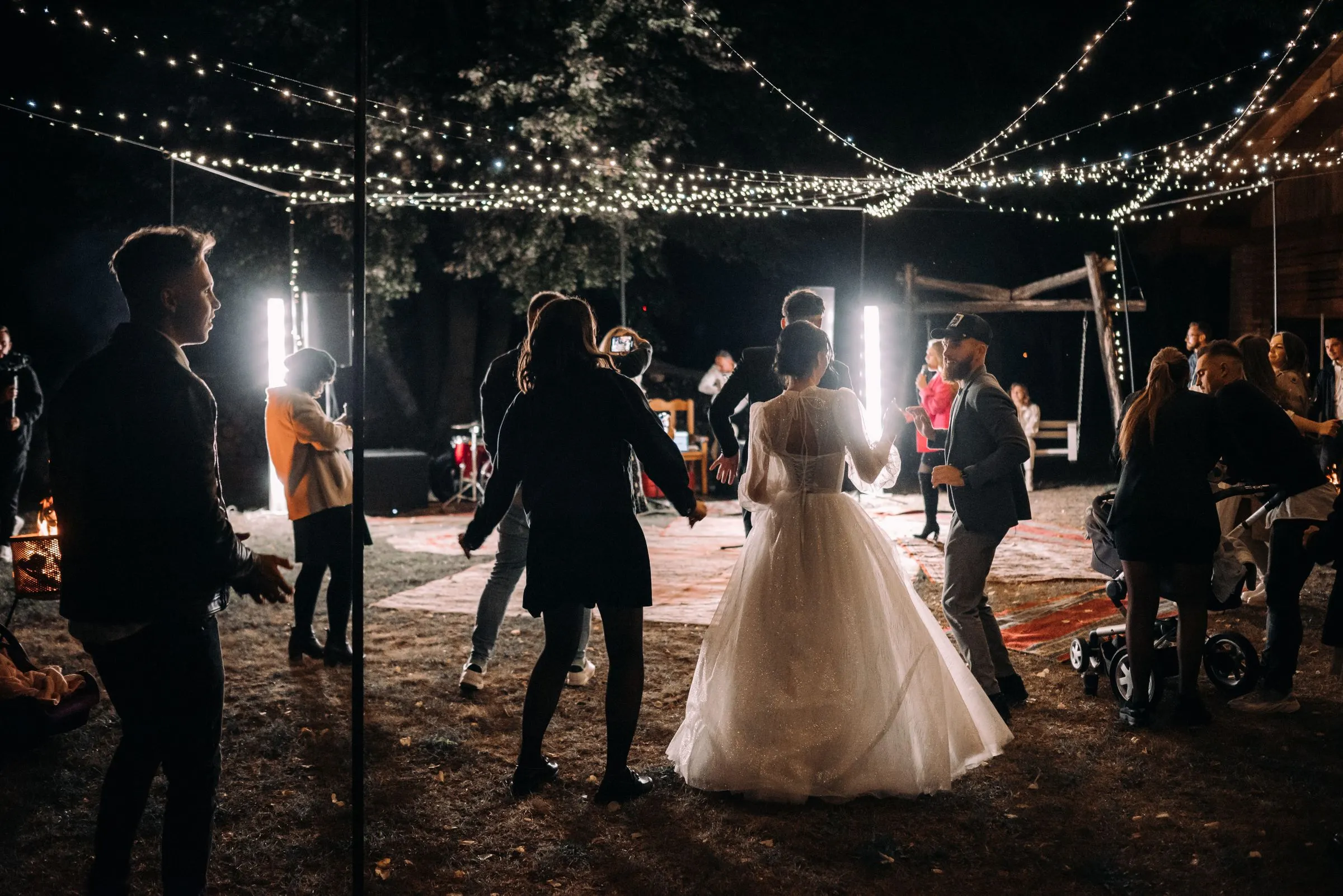 The couple and their guests dance under strings of lights in a garden at night